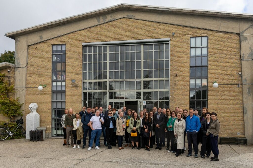 Photo: The participants in front of the Zentropa film studio, adapted in 1999. Previously, it housed barracks, and the visible building served as a hangar for tank repairs